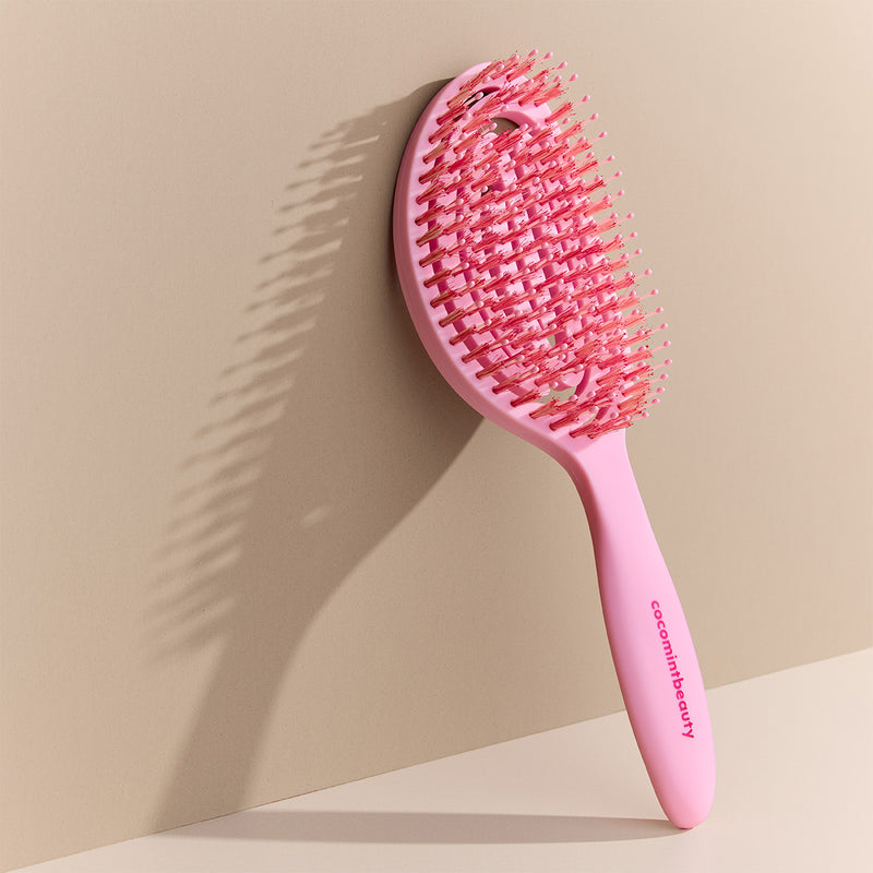 Pink hairbrush with 'cocomintbeauty' branding on a beige background