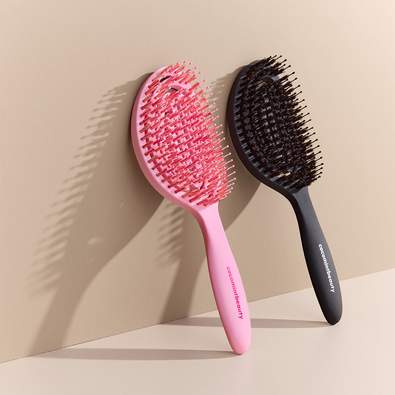 Pink and black hairbrushes on a beige background