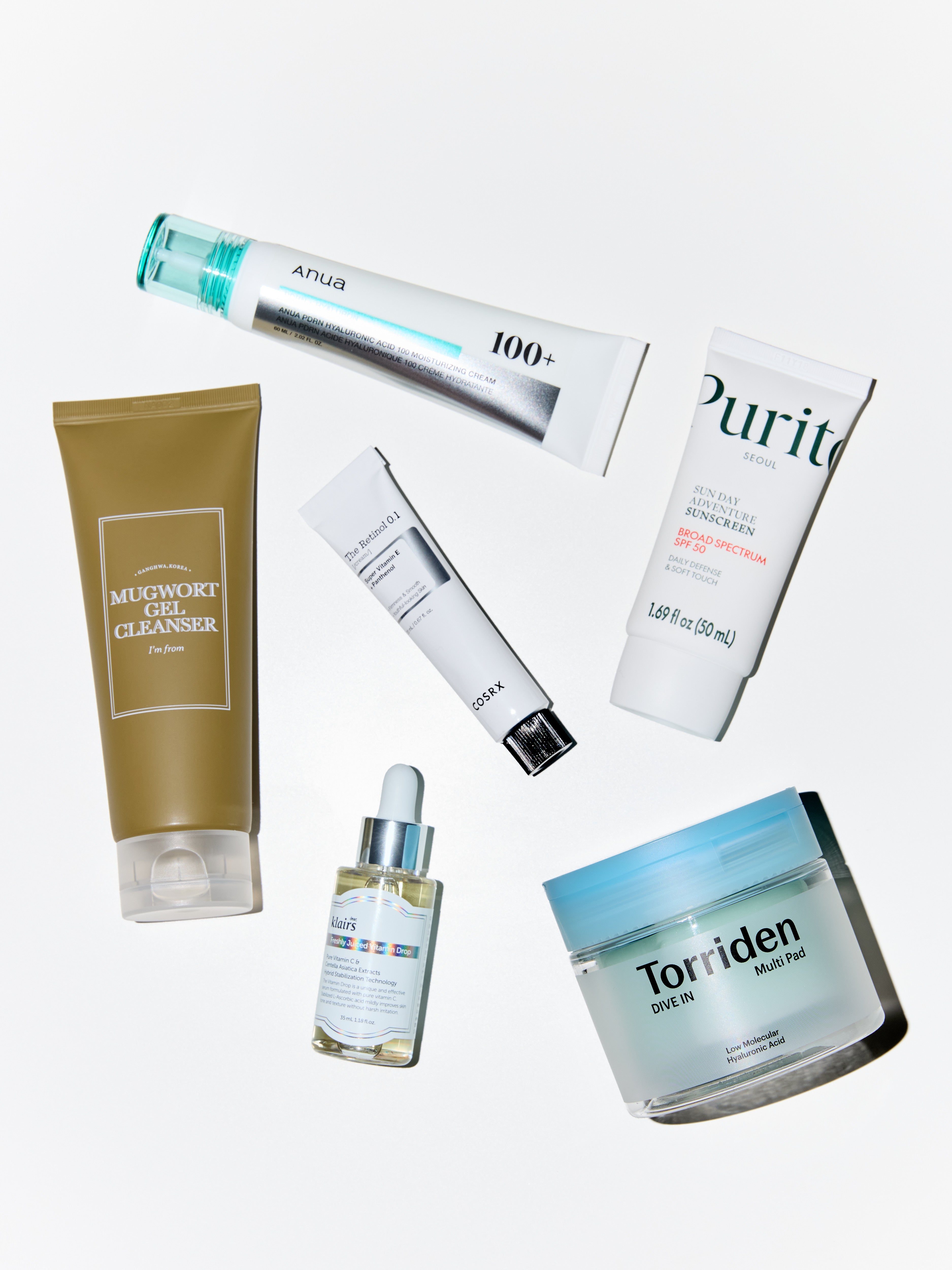 Collection of skincare products including a tube, cream, and jar on a light gray background