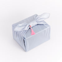 Cocomint Beauty Korean skincare gift set wrapped in blue silk Bojagi with a delicate pink Norigae tassel. Perfect K-beauty gift for her.