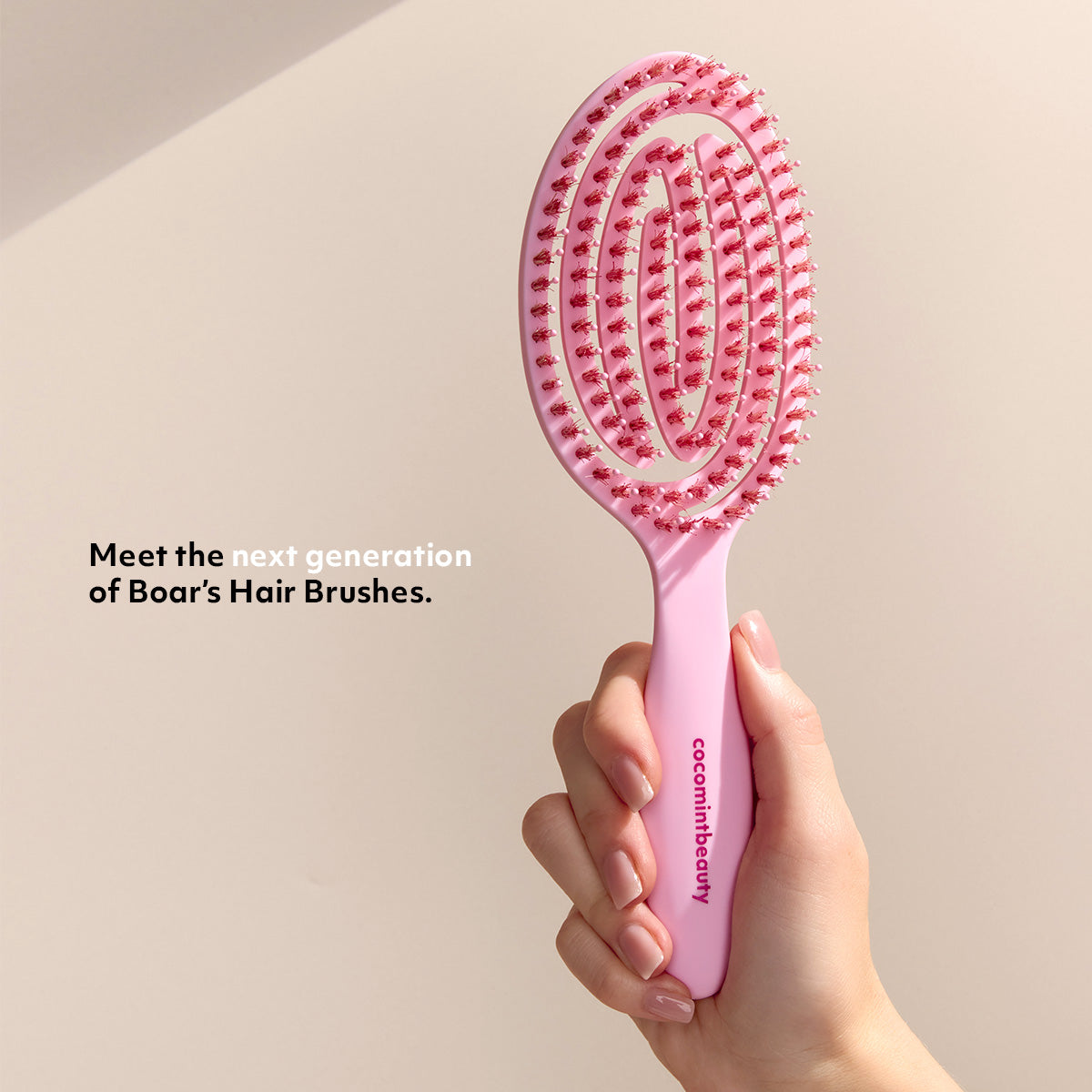 Pink boar's hair bristle brush from Cocomint Beauty held in hand