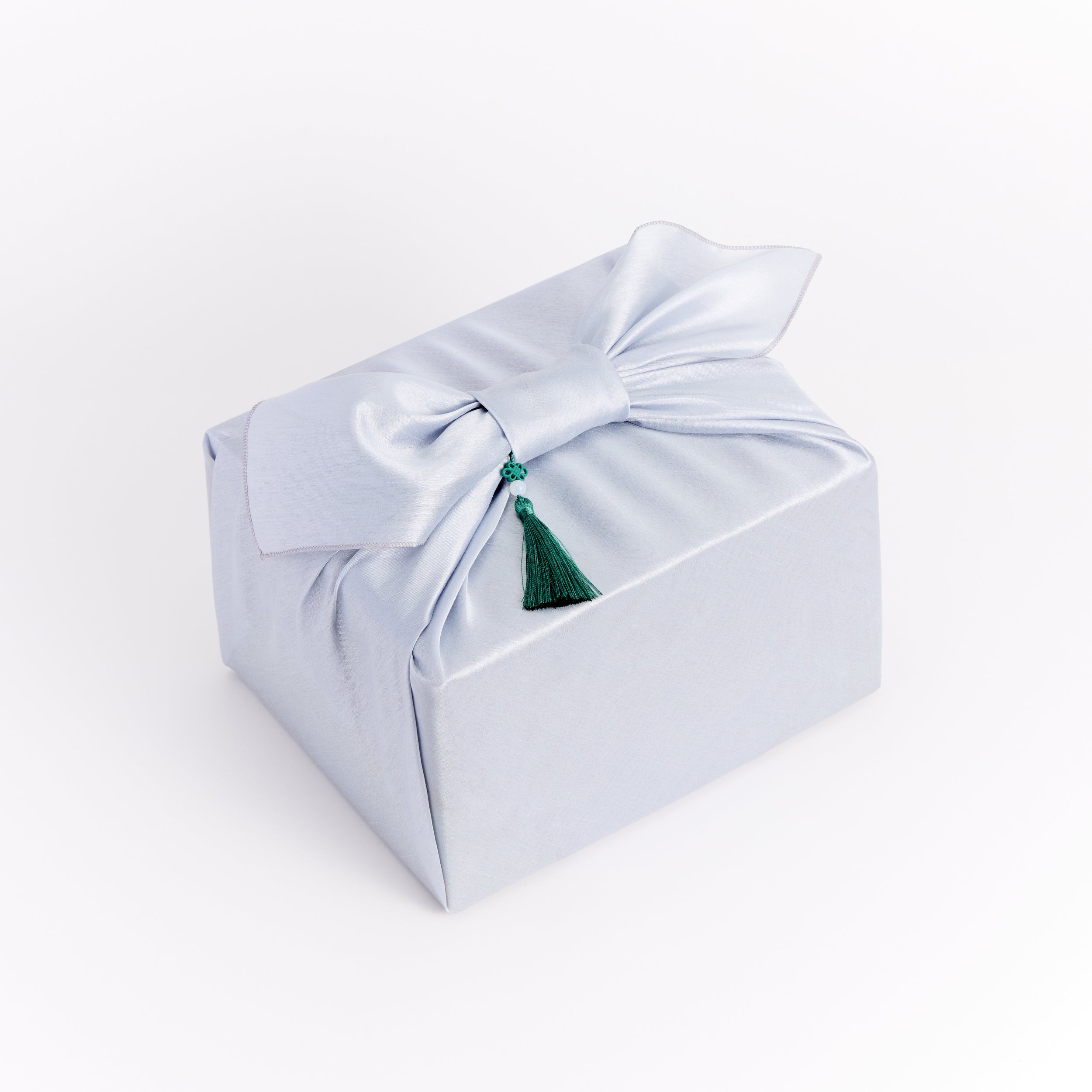 Traditional Korean gift packaging by Cocomint Beauty with blue silk wrap and a deep green tassel accent. Authentic K-beauty aesthetics.